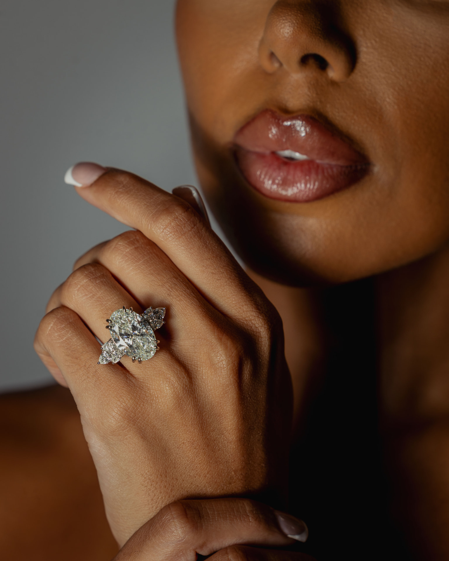 An oval diamond ring with pear-shaped side stones, worn on the hand