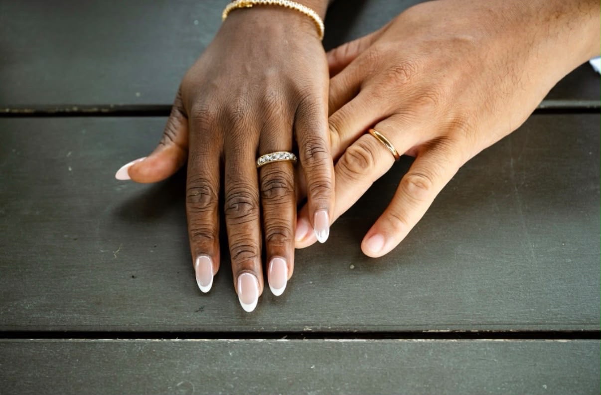 A couple's hands with a diamond eternity band and a plain gold wedding band